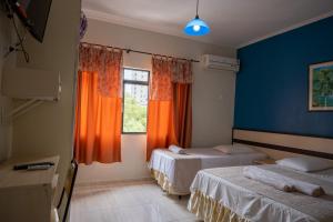 Habitación con 2 camas y ventana con cortinas de color naranja. en Seibt Palace Hotel, en Foz do Iguaçu