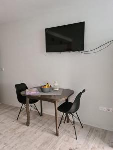 a table with two chairs and a television on a wall at Апартамент (Студио) Тони in Veliko Tŭrnovo