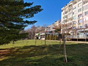 a park in front of a building with a tree at Апартамент (Студио) Тони in Veliko Tŭrnovo