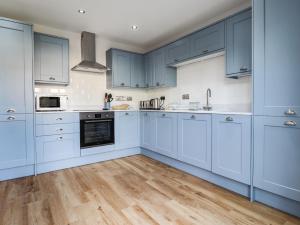 a kitchen with blue cabinets and a wooden floor at 4 Llain yr Eglwys in Newport Pembrokeshire
