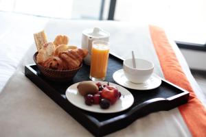 a breakfast tray with a plate of food and a cup of orange juice at Atlantic Hôtel & Spa in Les Sables-d'Olonne