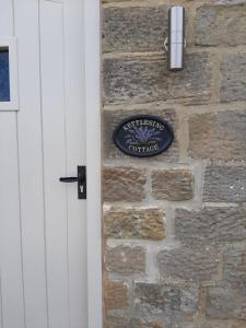 ein Schild an einer Steinmauer neben einer Tür in der Unterkunft Kettlesing Cottage, Harrogate in Harrogate + 3 Fotos