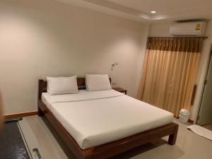 un letto con lenzuola e cuscini bianchi in una stanza di SB Mansion a Buriram