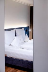 Schlafzimmer mit einem Bett mit weißer Bettwäsche und Kissen in der Unterkunft Hotel Walserwirt in Wals