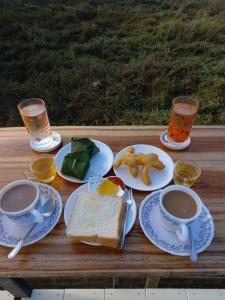 una mesa de madera con platos de comida y tazas de café en มองนาวิว @น่าน, en Nan
