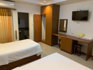 ein Schlafzimmer mit einem Bett und einem Schreibtisch mit Fernseher in der Unterkunft SB Mansion in Buriram