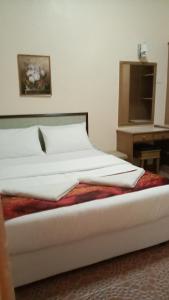 a bed with white sheets and a table in a room at Apartment Teluk Batik in Lumut