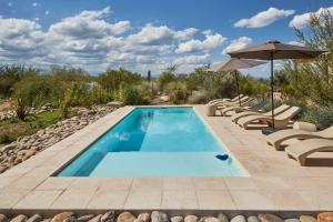 a swimming pool with chairs and an umbrella at Casa de Huéspedes Bodega Gimenez Riili in Los Sauces