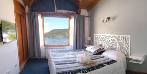 Schlafzimmer mit einem Bett und einem großen Fenster in der Unterkunft Cabañas Lago Soñado de los Andes in San Martín de los Andes