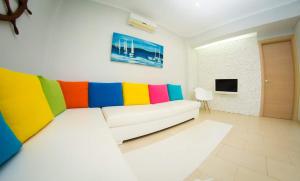 a white couch with colorful cushions in a living room at Colors Of The Sea in Leptokarya