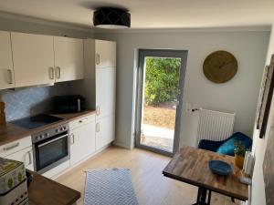 eine Küche mit weißen Schränken, einem Tisch und einer Tür in der Unterkunft Schöne Wohnung mit Ausblick und Gartensitzplatz in Lörrach