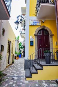 a yellow building with a red door and stairs at Residence Marina Corta in Lipari