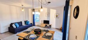 a living room with a blue couch and a table at A 2 PAS DU LAC - WIFI - Garage - Netflix - Disney+ - Lac in Sévrier