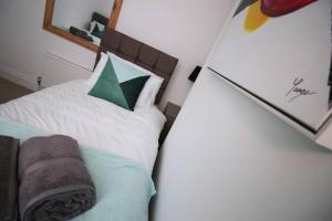 a small bedroom with a white bed with green pillows at Goodrich Mews in Newport