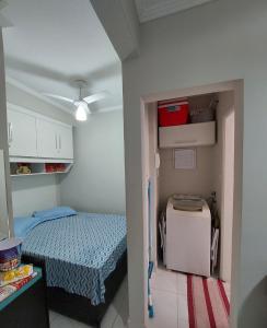 um pequeno quarto com uma cama e um pequeno frigorífico em Apartamento Edifício Turim Ponta da Praia Santos em Santos