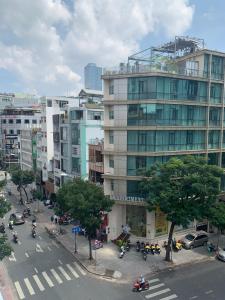 a city street with a large building with cars and motorcycles at Little Brick Saigon Hotel in Ho Chi Minh City