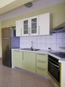 eine Küche mit weißen Schränken und einem Kühlschrank aus Edelstahl in der Unterkunft Apartment Alena 1 i 2 in Bibinje