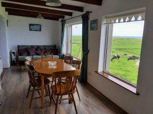una sala da pranzo con tavolo, sedie e una finestra di Doonbeg Holiday Cottages a Doonbeg