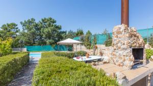 een achtertuin met een stenen open haard naast een zwembad bij Villa Ara - Lloret de Mar in Mont Barbat