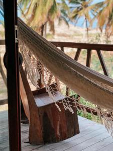 a hammock on a porch with palm trees in the background at Pousada Vayú in Icaraí