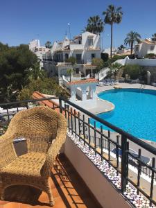 une chaise en osier assise sur un balcon à côté de la piscine dans l'établissement Villa an der Costa Blanca, à Villacosta