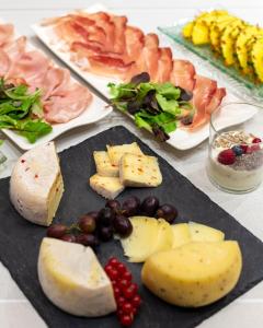 a table with different types of cheese and grapes at Hotel Pareda in Canazei