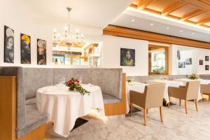 a restaurant with tables and chairs and a chandelier at Hotel Pareda in Canazei