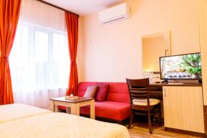 Habitación de hotel con sofá rojo y escritorio. en Villa Gamma, en Pavel Banya