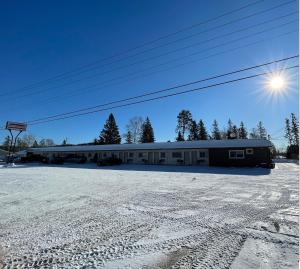 a building in the snow with the sun behind it at Village Inn & Suites - Sudbury in Lively