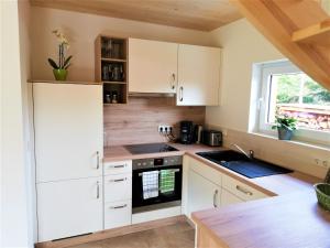 a kitchen with white cabinets and a sink and a window at Fewo bei Reuters - Haus Tellkoppe in Waldidylle