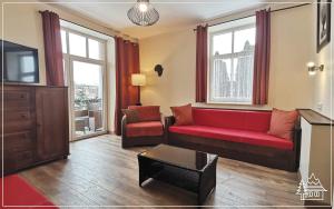 - un salon avec un canapé rouge et une télévision dans l'établissement Przystanek Rabka - Apartamenty w centrum, à Rabka-Zdrój