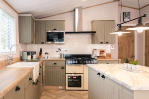 a kitchen with white cabinets and a stove top oven at The White Rose Lodge with Hot Tub in York