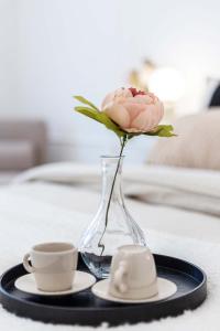 a vase with a pink rose and a cup of coffee at Appartamento Corfù in Lido di Ostia