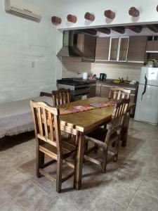 cocina con mesa de madera con sillas y nevera en Amaru Apart en La Consulta