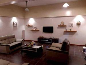 a living room with couches and a flat screen tv at 4-6人家庭 Cozy Home @ Kutoba Square in Tawau