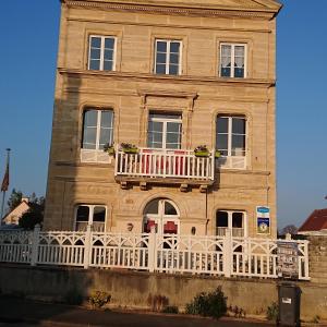 ein Gebäude mit einem Balkon mit amerikanischer Flagge in der Unterkunft JOYEUX REVEIL in Courseulles-sur-Mer