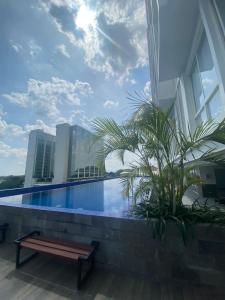 una piscina al lado de un edificio con un banco en The yudhistira apartment en Yogyakarta