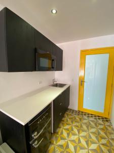a kitchen with black cabinets and a yellow door at Hotel Nest in San Juan