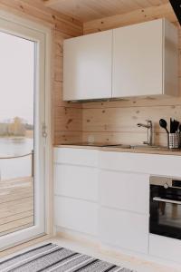 una cocina con armarios blancos y una ventana en Villa Varis, en Jorvas