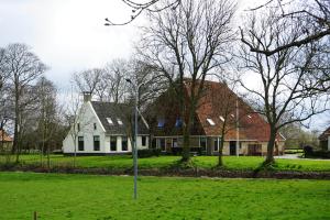 a white house with trees in a green field at B&B Piebengastate Welsrijp in Welsrijp