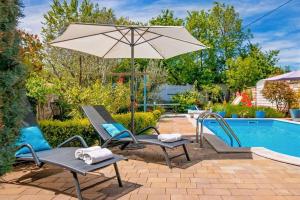 a pair of chairs and an umbrella next to a pool at Villa Kažun with private pool and two gardens in Marčana