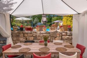 a wooden table with red chairs and a white umbrella at Villa Kažun with private pool and two gardens in Marčana