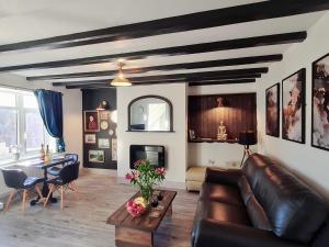 uma sala de estar com um sofá de couro e uma mesa em Bensons Gem - Cyanacottages em Whitby