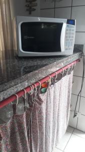 a kitchen counter top with a microwave on top of it at Aconchego 3 dorms, piscina, churrasq em Condomínio Fechado in Boicucanga