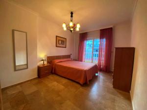 1 dormitorio con cama, ventana y lámpara de araña en Apartamento Coliseo Almuñecar, en Almuñécar