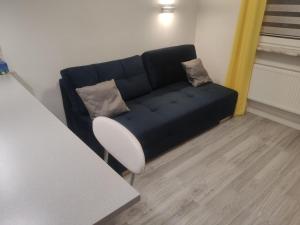 a black couch in a living room with a white chair at Comfortable Studio only 20 minutes from International Conference Center Katowice best place for WUF2022 EEC TNF OFF etc in Siemianowice Śląskie