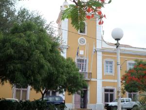 un bâtiment jaune avec une horloge sur son côté dans l'établissement Casa Privada do Plateau, à Praia