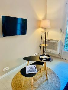 a living room with a table and a tv on a wall at Chez Garance Saint-Tropez in Saint-Tropez
