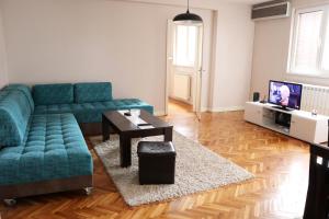 a living room with a blue couch and a table at Spacious modern apartment Aerodrom in Skopje