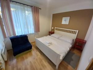 a bedroom with a white bed and a blue chair at Apartmány Margo Sun in Martinske Hole